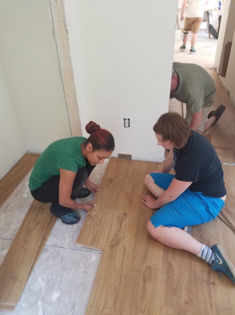 volunteers install laminate flooring